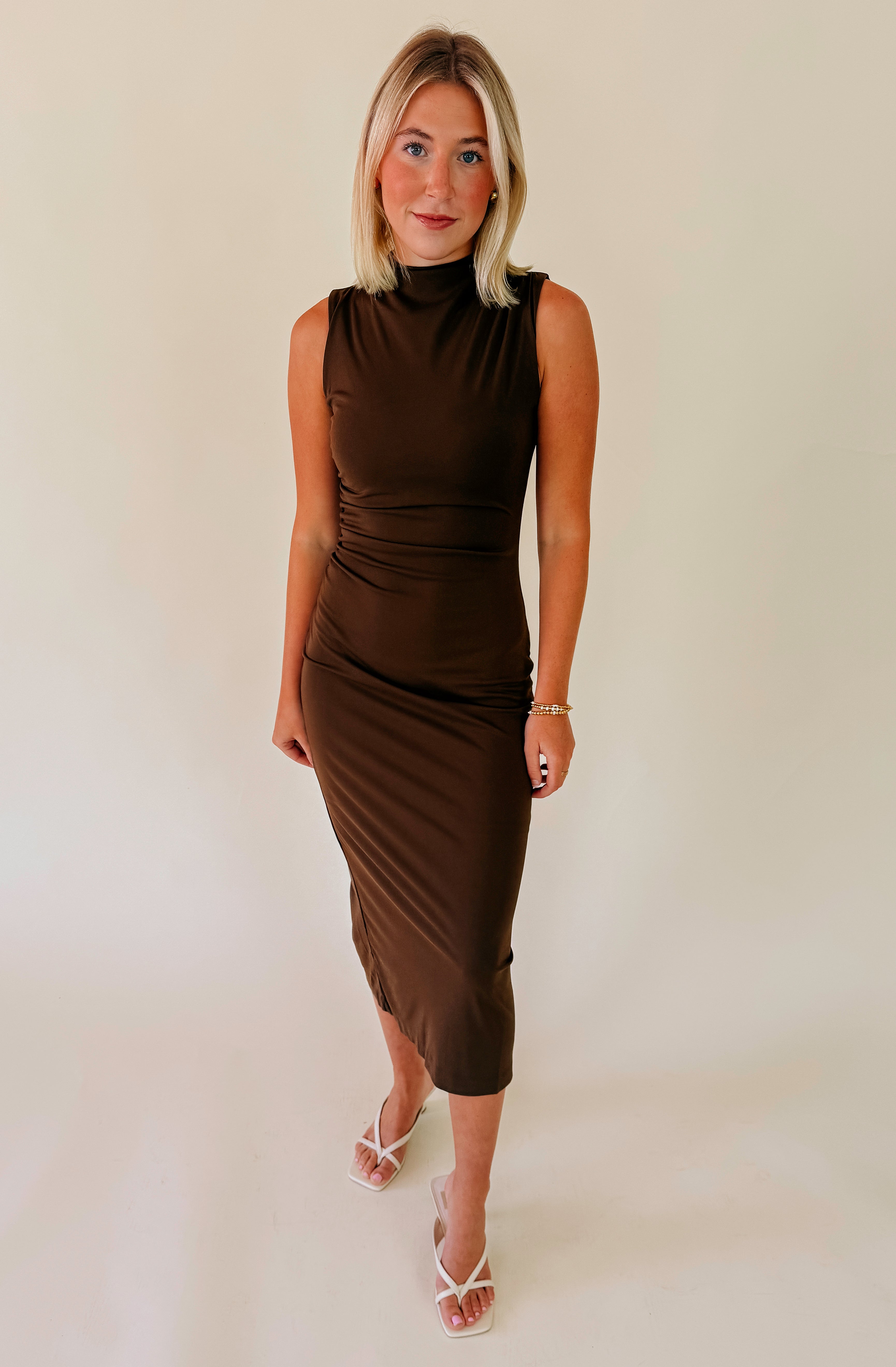 Woman wearing a brown dress against a plain background