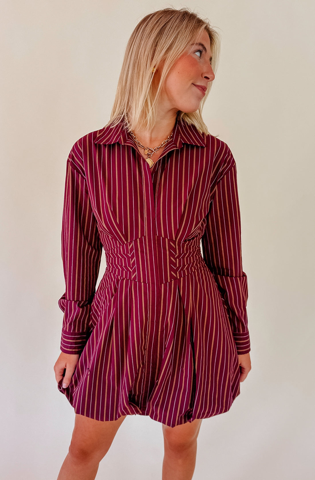 Woman wearing a maroon and white striped dress against a plain background